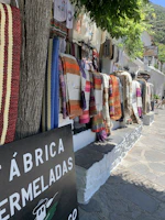 Artisan-crafted huipiles hanging against a backdrop of hand-painted Oaxacan murals.