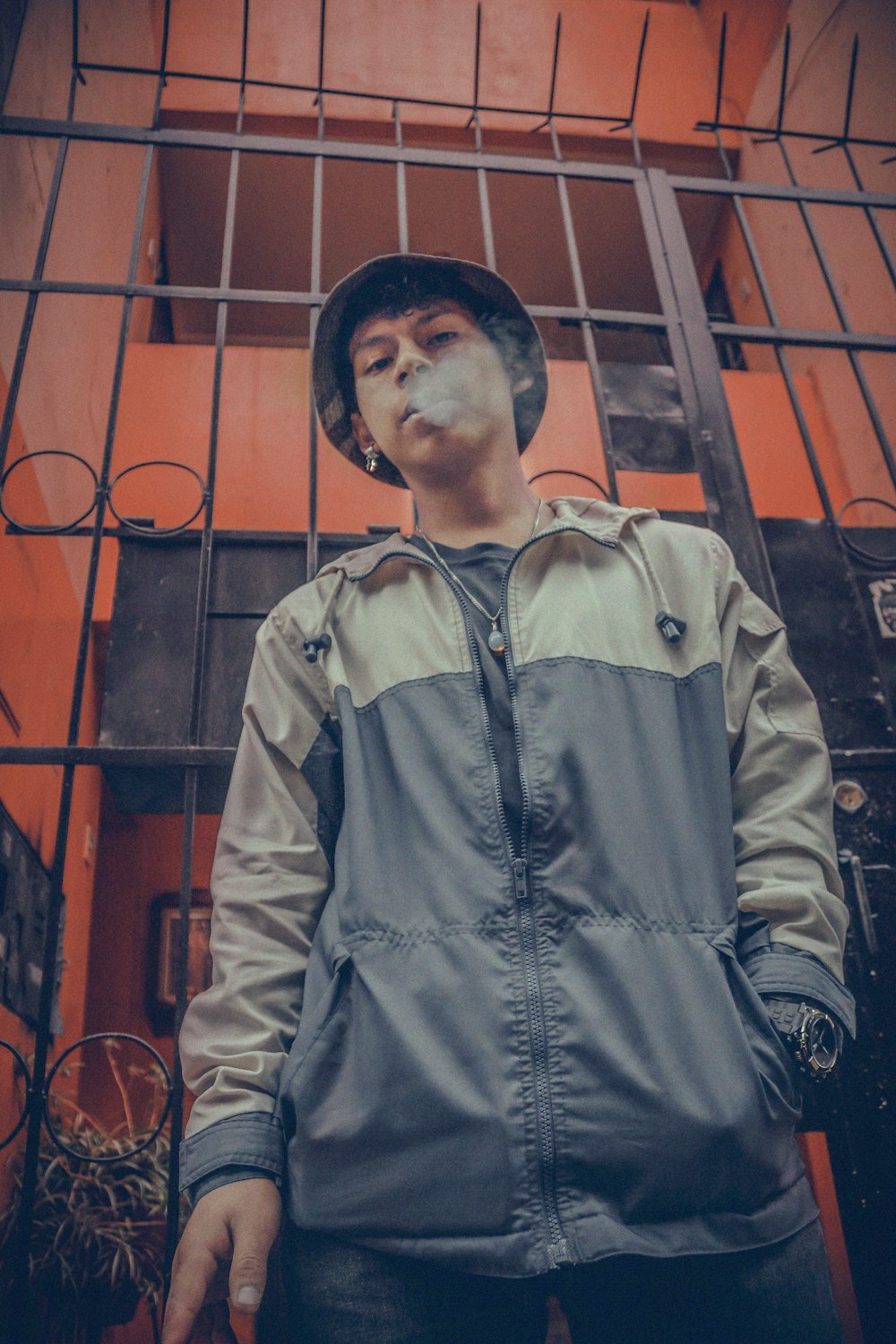 man in gray jacket standing beside metal gate