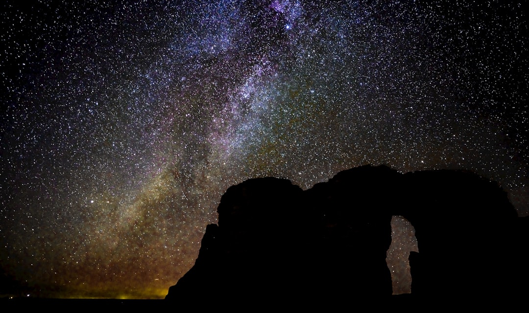 silhouette of rock mountain under galaxy at night time