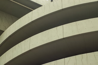 Curved sections of a concrete structure with visible lines and textures, likely part of a modern architectural building.