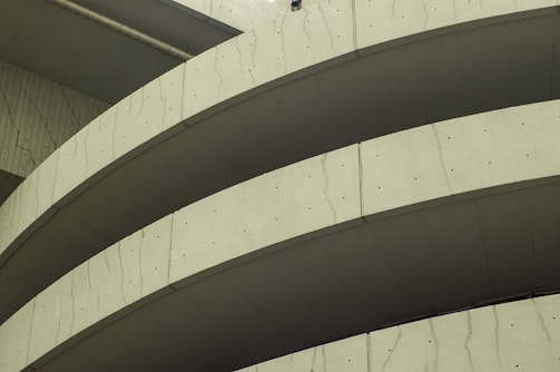 Curved sections of a concrete structure with visible lines and textures, likely part of a modern architectural building.
