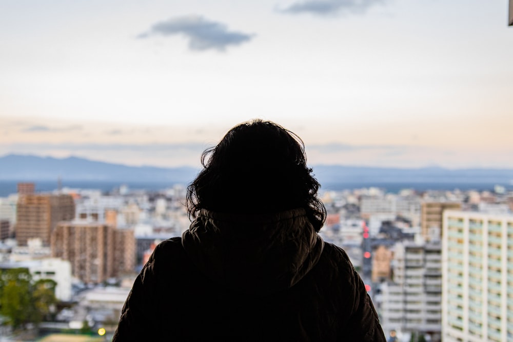 街を見下ろす窓の前に立っている人