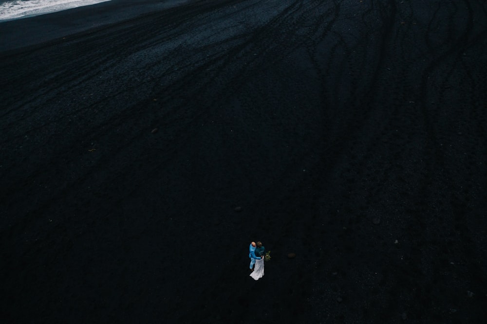 a person standing in the middle of a black sand beach
