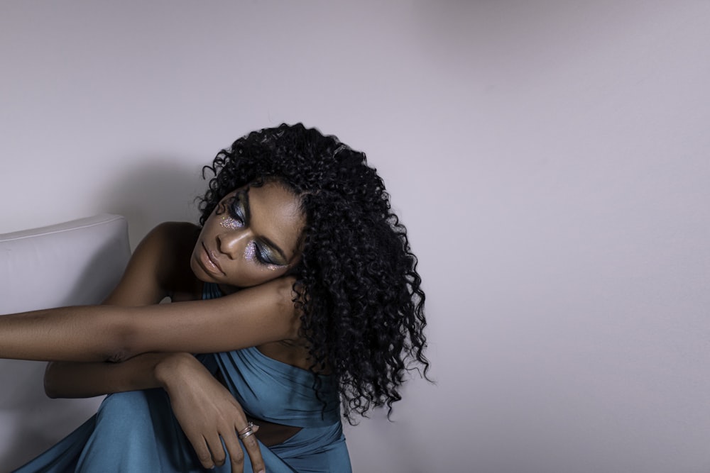 woman in blue top sitting beside wall