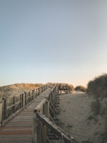 A wooden boardwalk weaving through dunes, guiding visitors to a peaceful Outer Banks beach.