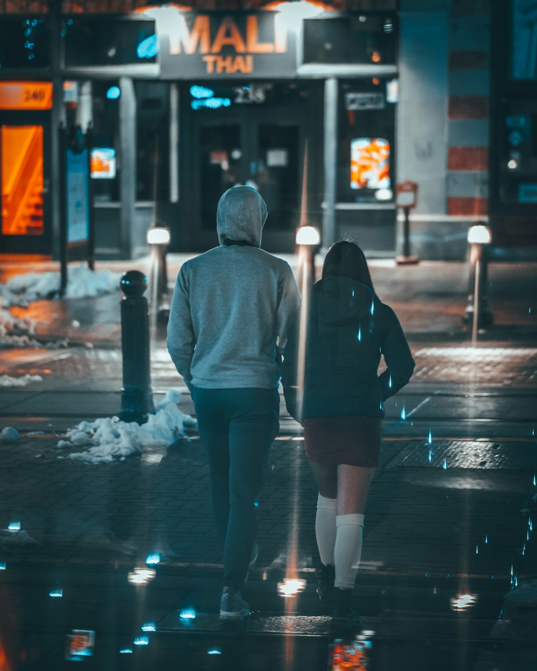 man and woman walking across road during nighttime