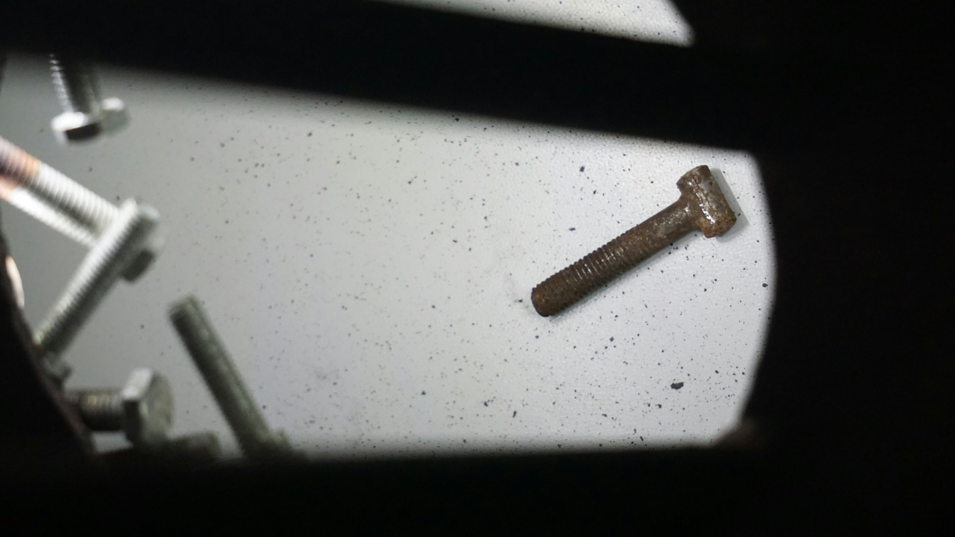 An assortment of screws and nuts scattered on a wooden surface, emphasizing their quality and variety.