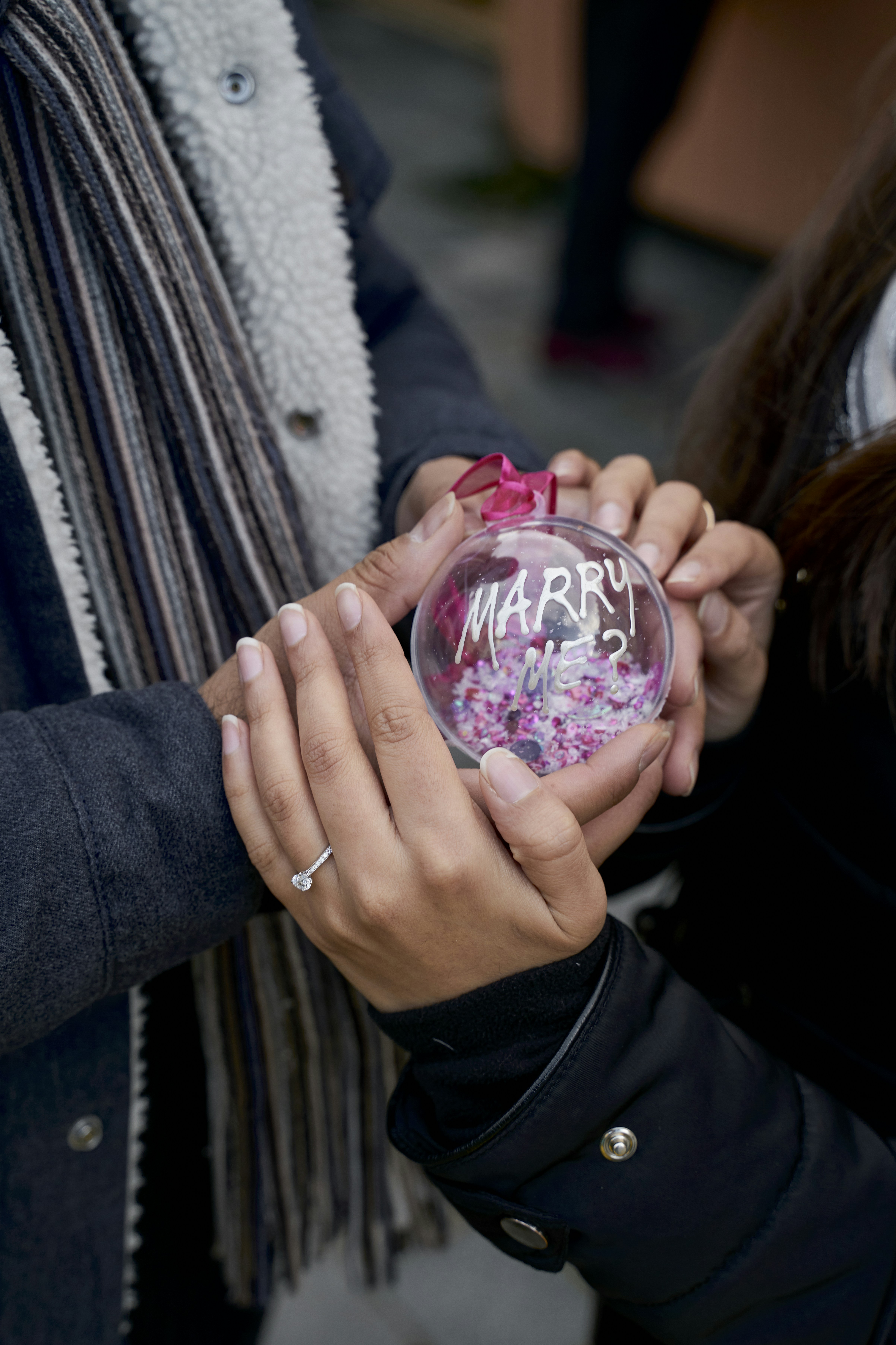 person holding Marry Me ball decor