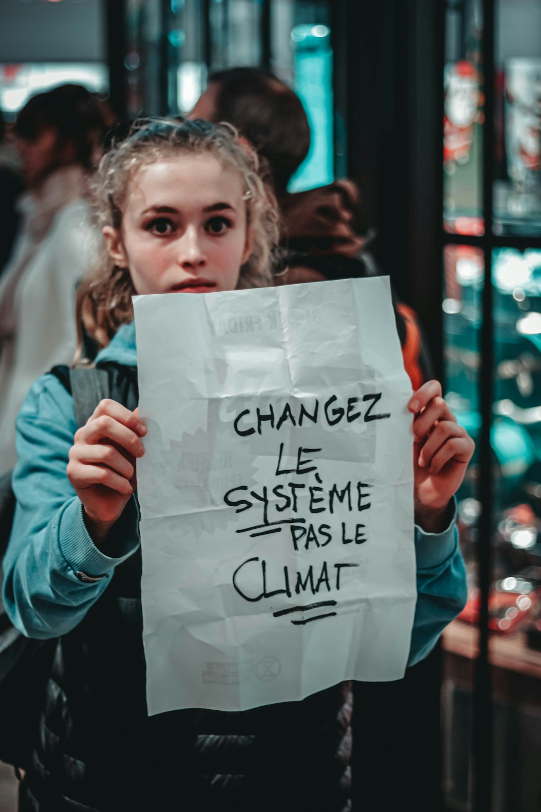 selective focus photography of woman holding Changez Le Systeme Pas Le Climat sign