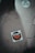 A sticker on the ground with the text 'STOP amazon et son monde' featuring a stop sign design. The sticker is positioned slightly off-center on a tiled floor which has visible cracks and dirt. Another round sticker with green text and graphics, related to activism, is partially visible.