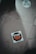 A sticker on the ground with the text 'STOP amazon et son monde' featuring a stop sign design. The sticker is positioned slightly off-center on a tiled floor which has visible cracks and dirt. Another round sticker with green text and graphics, related to activism, is partially visible.