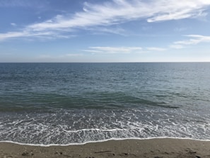 A scenic view of a calm beach with gentle waves and a clear sky