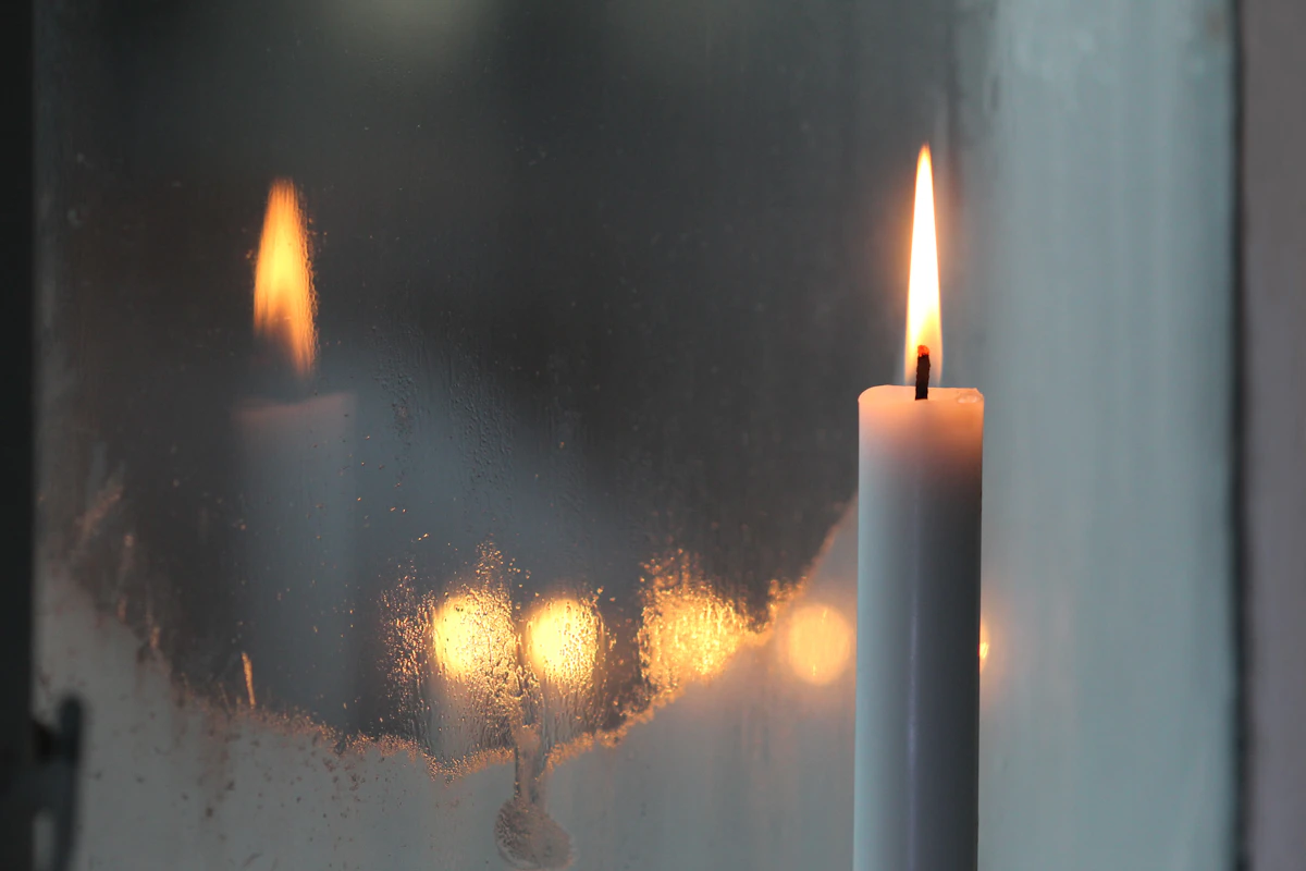 Lit candles glowing in a dark window