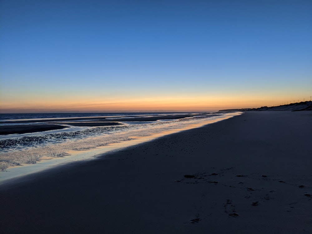 a beach at sunset with footprints in the sand