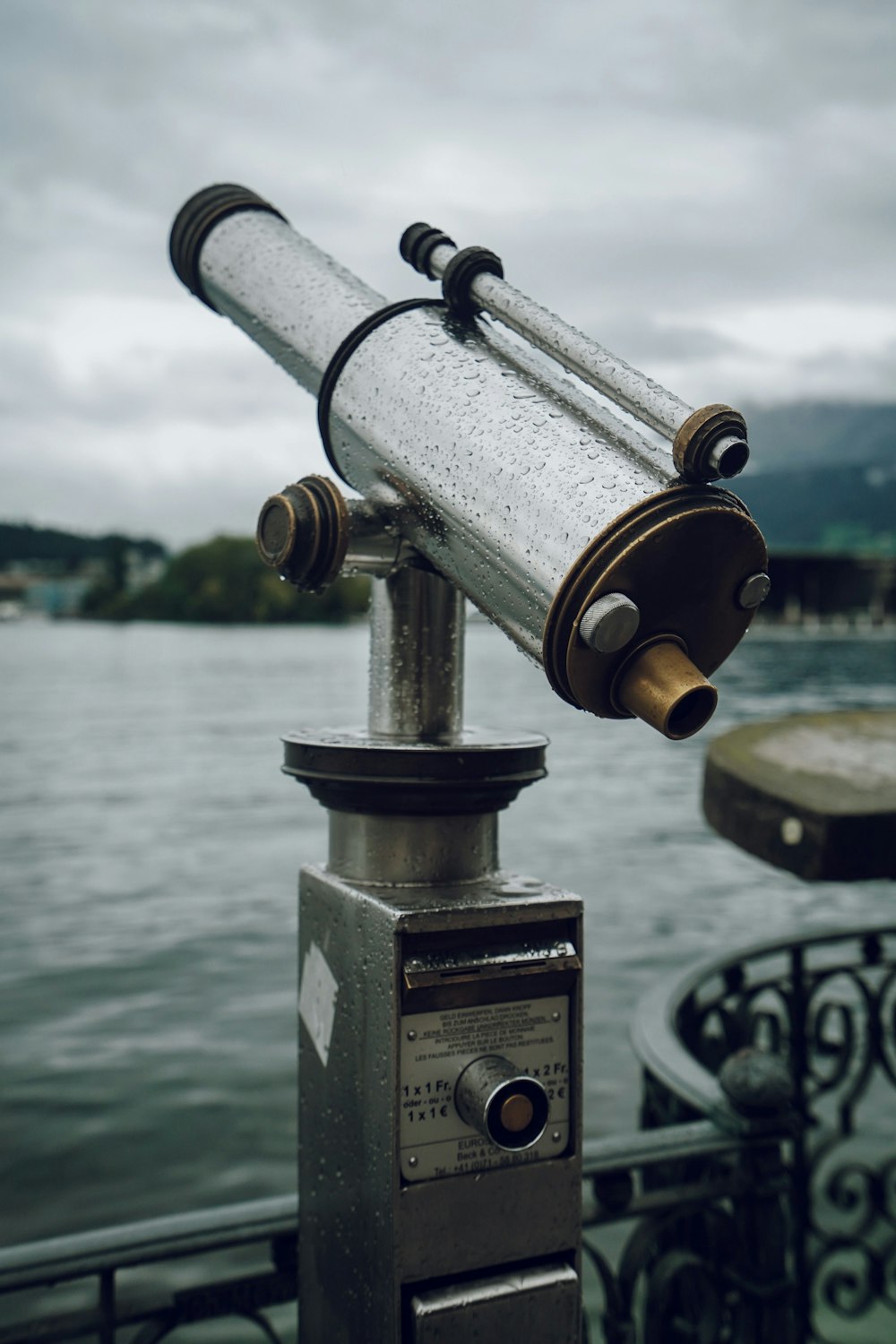 public telescope beside railing facing the body of water during day