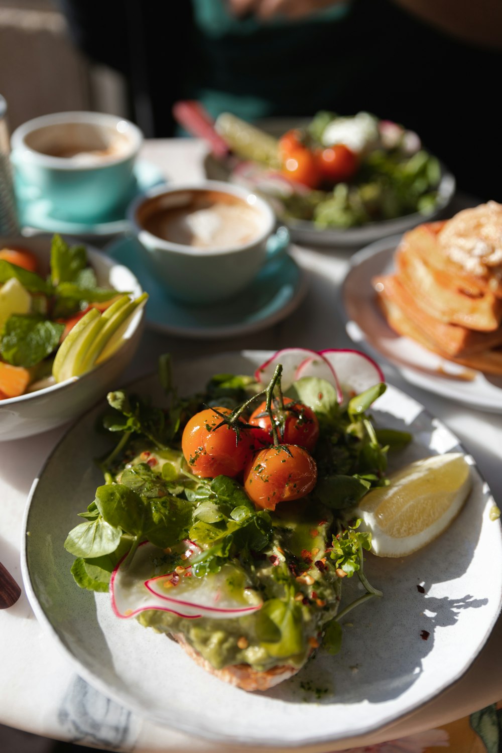 a white plate topped with a salad next to other plates of food