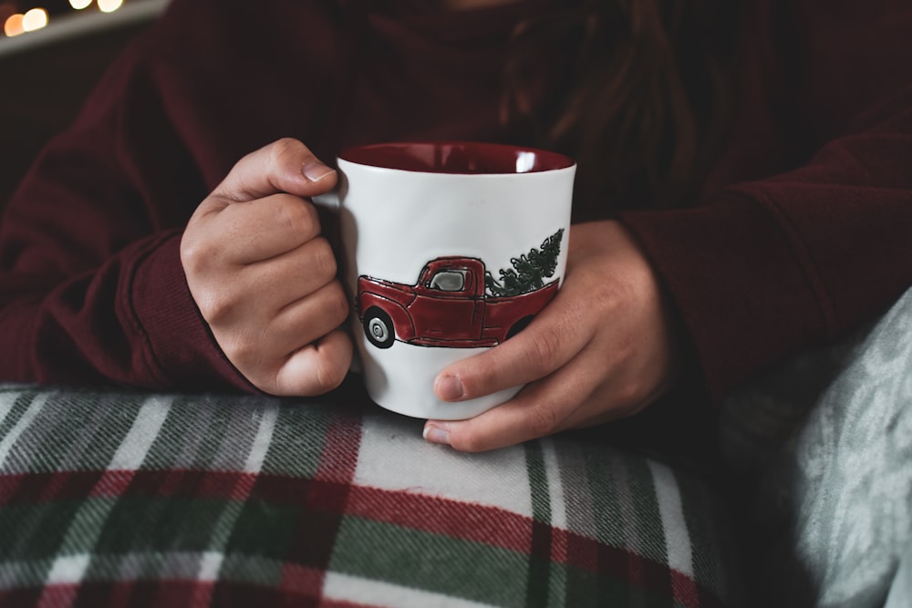 personne tenant une tasse en céramique blanche