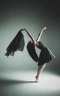A dancer gracefully arching back on the pole, bathed in soft neutral tones and shadow.