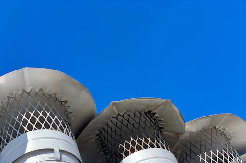 Close-up of a firefighter-style chimney cap being installed on a rooftop under a clear sky.