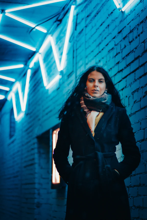 Woman in a black coat under neon light