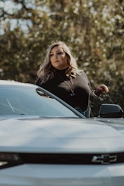 A woman advisor assisting a client with motor insurance paperwork beside a car.