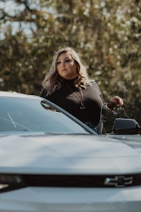 A woman advisor assisting a client with motor insurance paperwork beside a car.