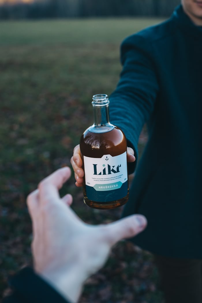 Scandinavian bottled drink being passed from one person to another: Beverage brands must invest in design, just as the pretty design in the picture shows.