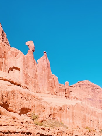 A dramatic desert landscape with towering red rock formations under a bright sky.