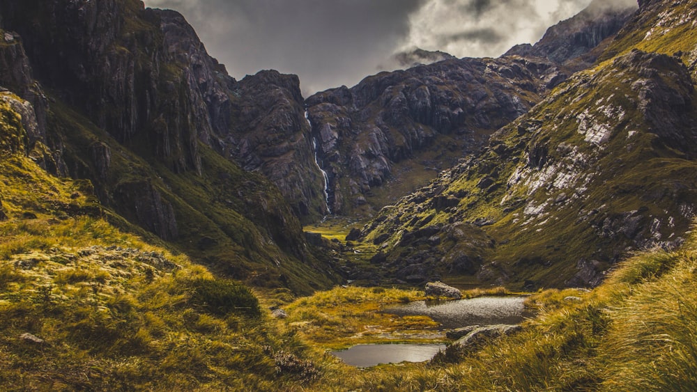 a mountain valley with a small pond in the middle of it