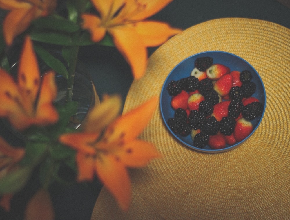 a blue bowl filled with fruit sitting on top of a table