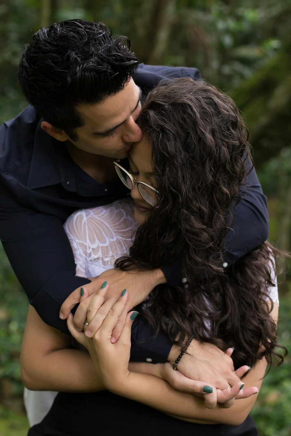 man hugging woman on her back and kissing her forehead