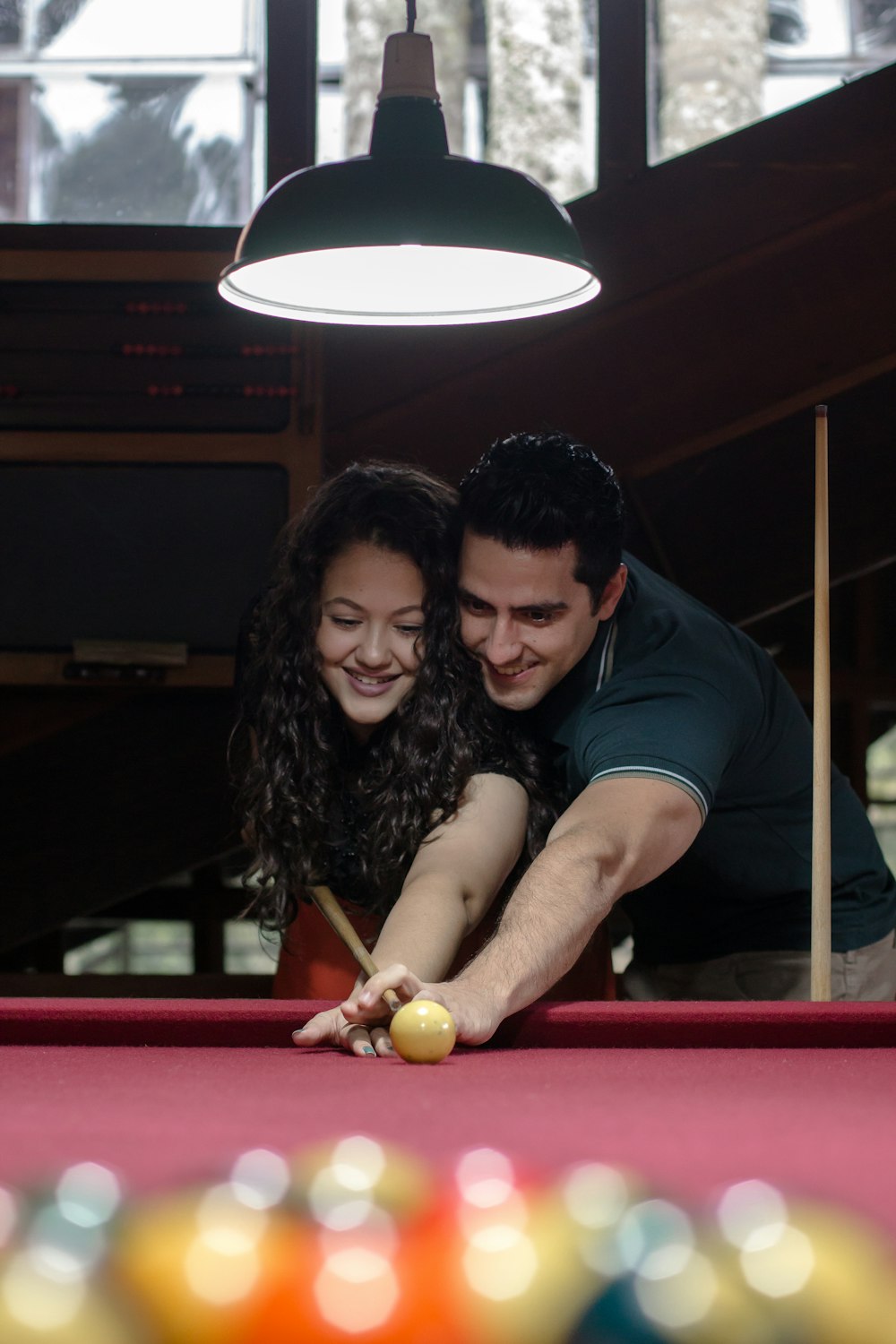 man teaching a woman how to play pool
