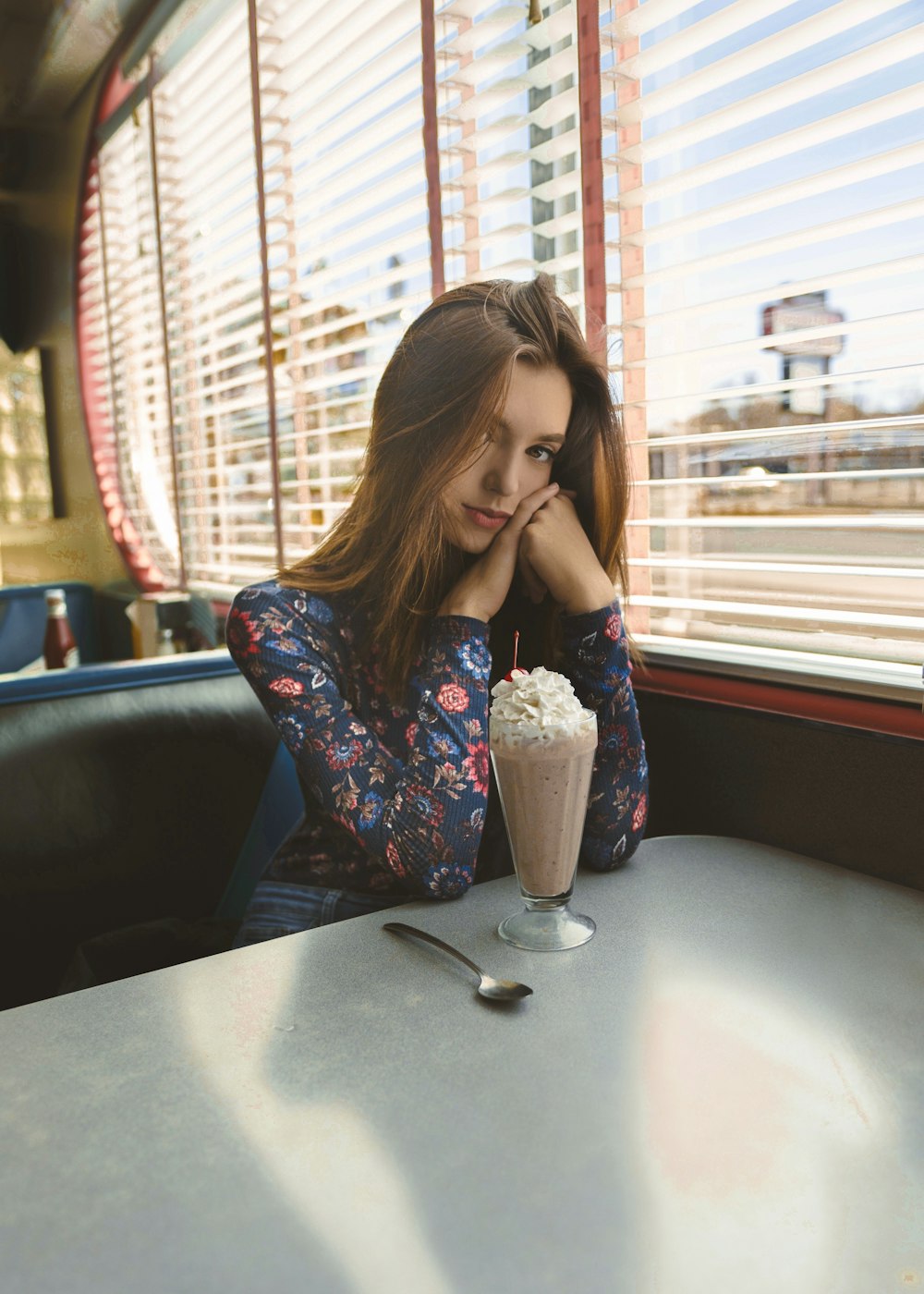 woman sitting in front of table beside window panel