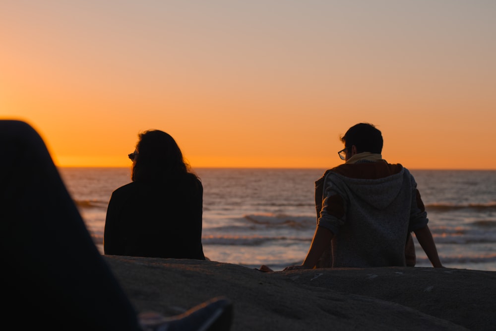 man and woman sitting near ocean