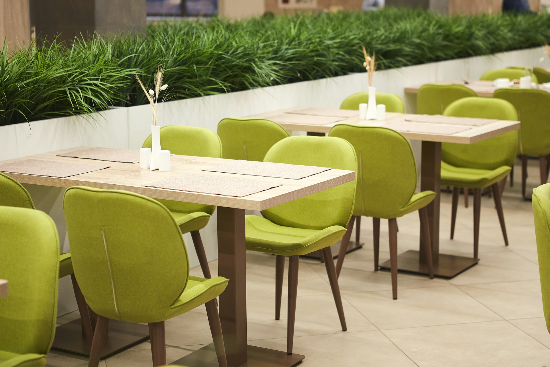 green padded chairs near beige tables