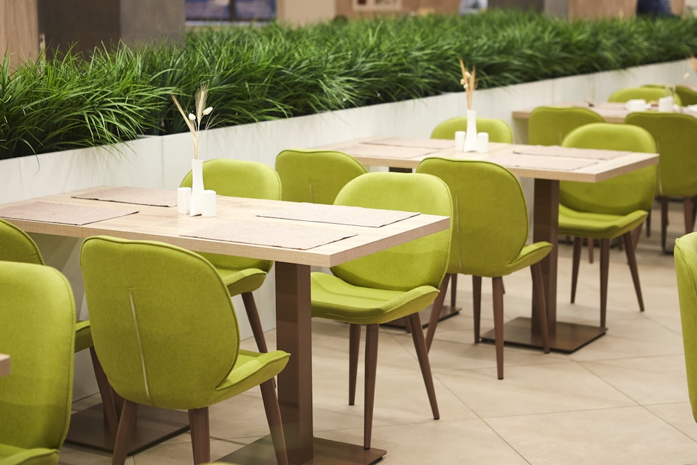 Grün gepolsterte Stühle neben beigen Tischen