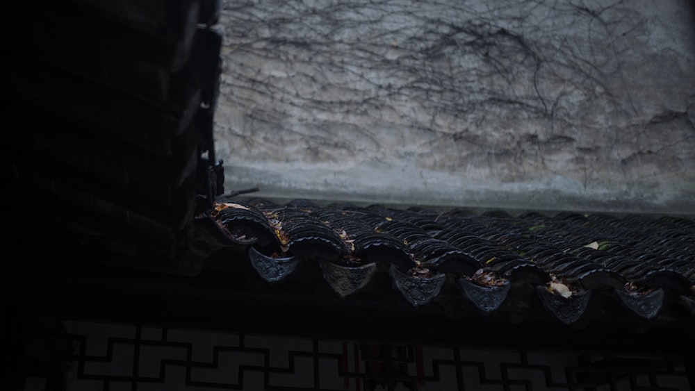 a close up of a roof with a stone wall in the background