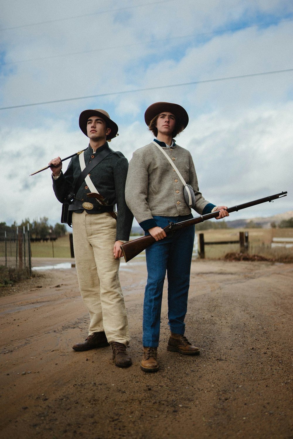 man holding rifle beside standing man