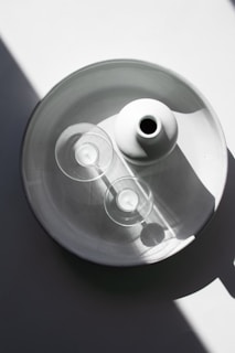 Minimalist plaster vase and candle set arranged on a white surface with greenery