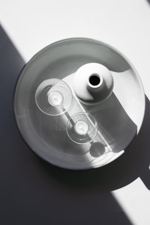 Minimalist plaster vase and candle set arranged on a white surface with greenery