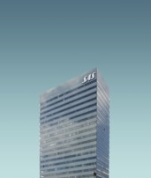 A tall, modern skyscraper with reflective windows and the letters 'SAS' displayed at the top. The building stands against a clear, cloudless sky.