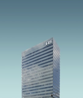 A tall, modern skyscraper with reflective windows and the letters 'SAS' displayed at the top. The building stands against a clear, cloudless sky.