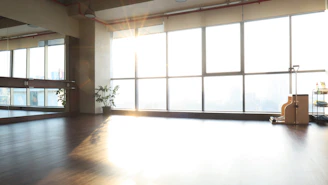 A sleek tide mill treadmill in a bright, airy home gym setting with sunlight streaming through large windows.