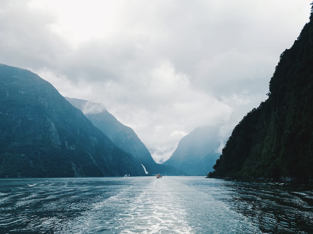 calm body of water in between of mountains