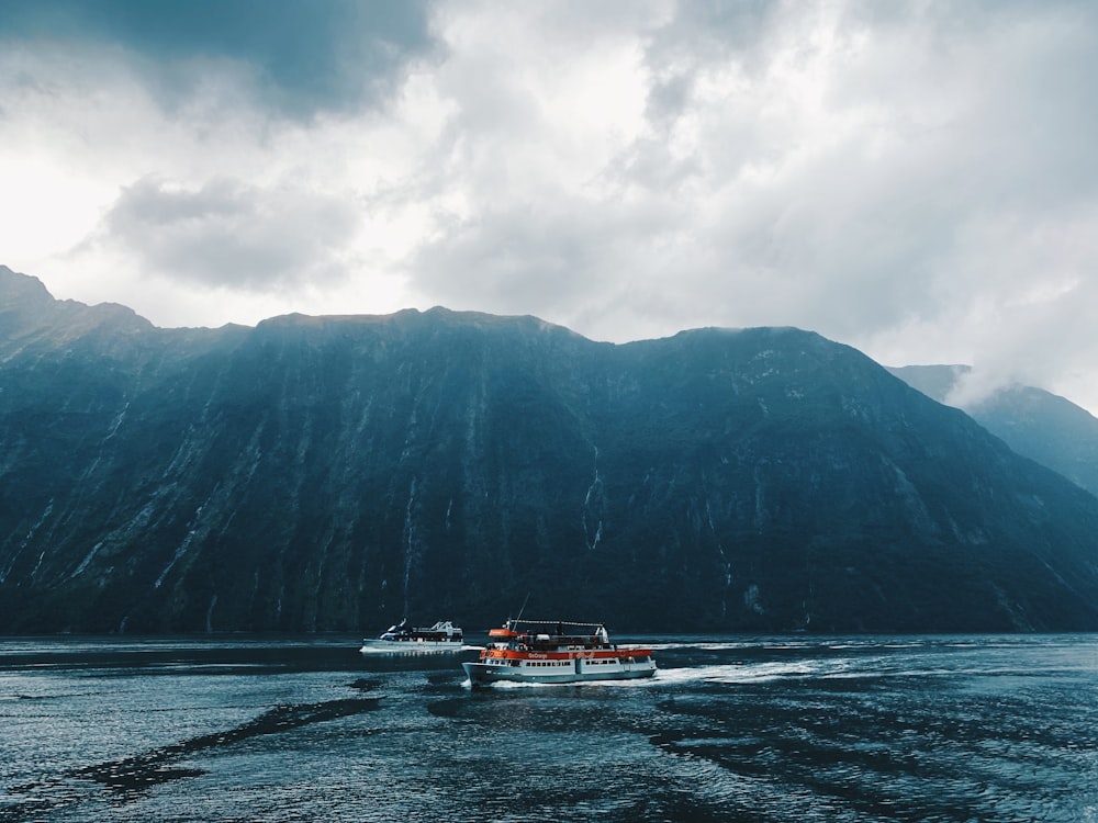 two ships floating on body of water near mountain during day