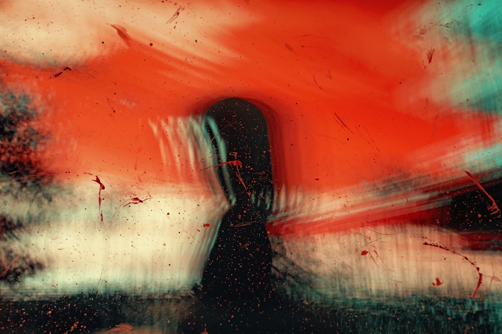 Una pintura de una persona parada frente a un cielo rojo