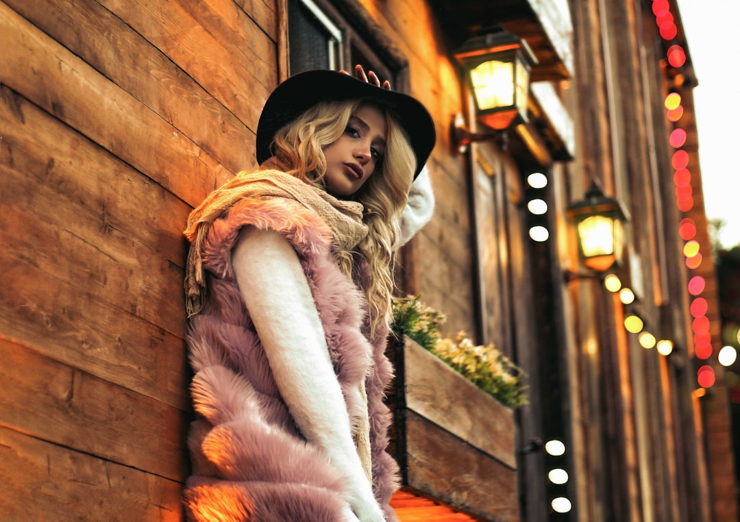 woman in pink fur vest leaning on wall