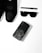 A collection of black fashion accessories including a pair of black sneakers, a black pen, black sunglasses, and a black smartphone with an artistic design on its case, arranged neatly on a white surface.