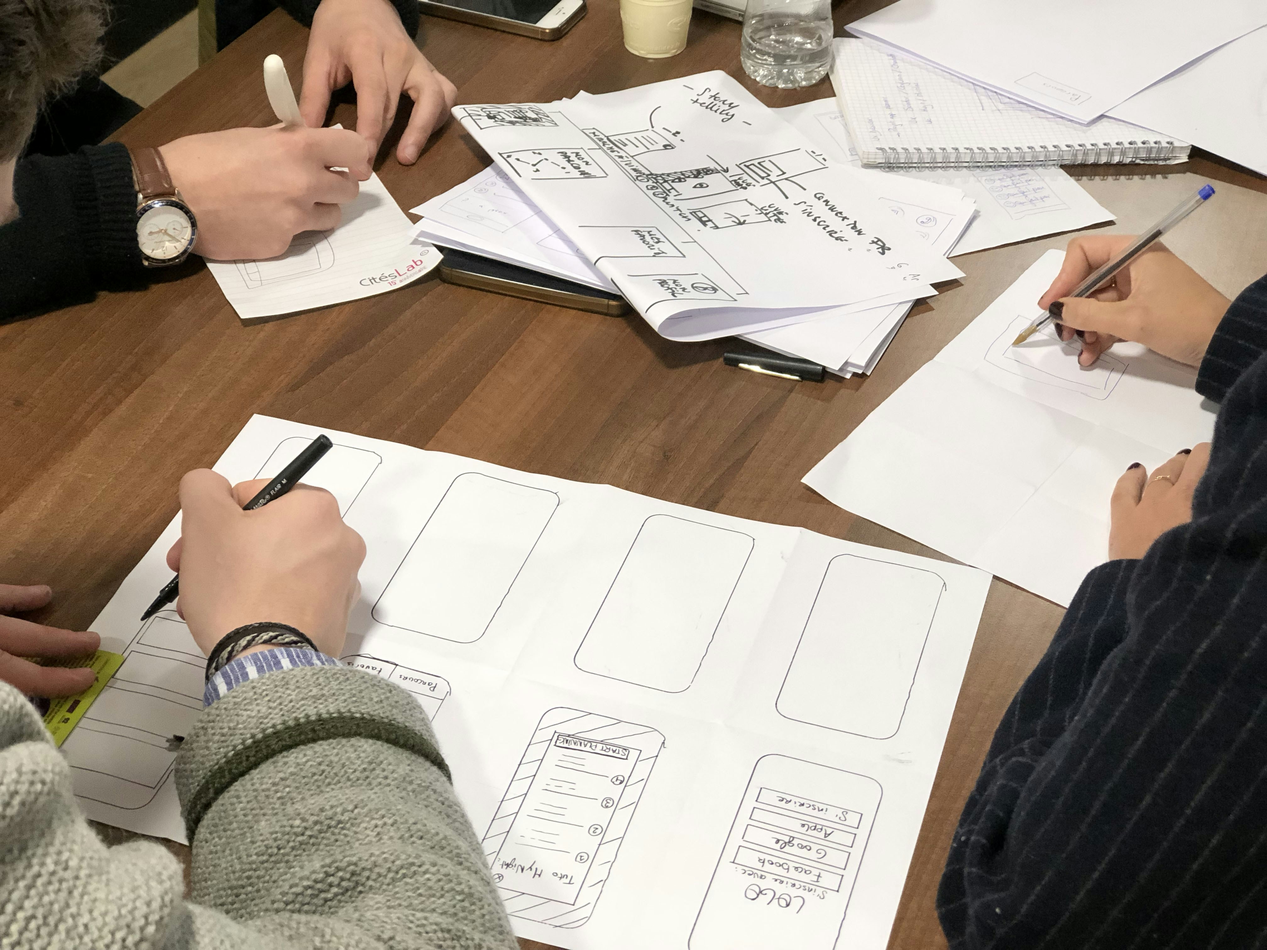 Design team collaborating around a dark table with screens and wireframes in a dimly lit studio