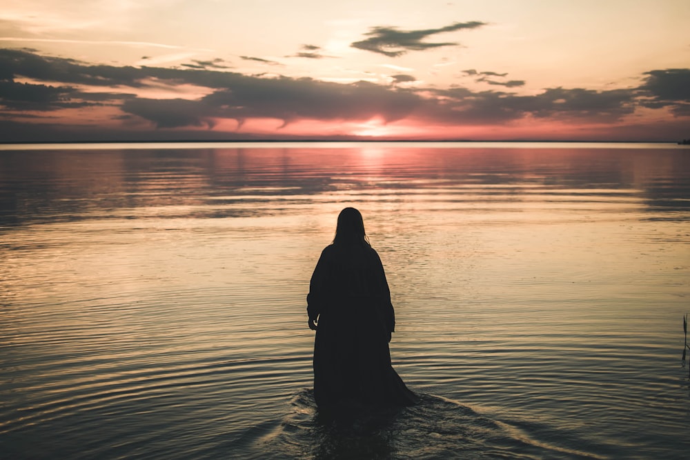 woman walking in sea during golden hour